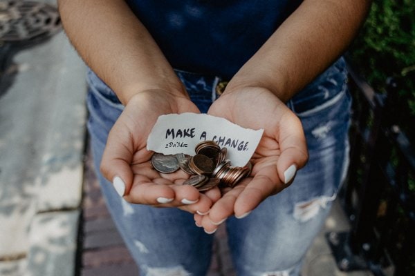 A Person holding a note and coins - make a change